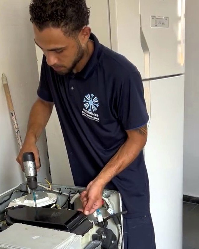 Profissional da Rodrigues Refrigerações avaliando uma máquina de lavar